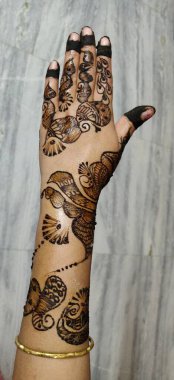 Gri arka planda siyah kına dövmeli Hintli gelin kızın elleri.