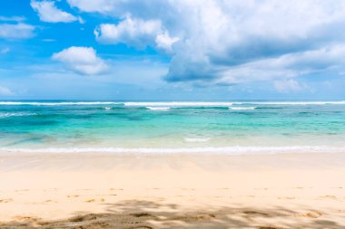 Dalgaların sahile vurduğu güzel deniz manzarası, Melasti Beach, Bali, Endonezya 'da beyaz bulutlar ve parlak mavi gökyüzü koleksiyonu..