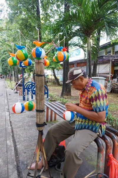 Cakarta, Endonezya, 23 Mart 2022: Çocuk oyuncakları satan şapkalı bir adam sabahleyin malını Jalan Kyai Tapa, Batı Jakarta 'nın yaya tarafında hazırlıyor..