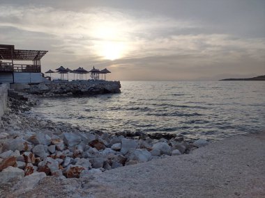 Denizde gün batımı. Deniz dalgaları üzerinde beyaz taşlarla harika bir sahil şeridi.