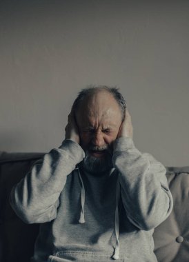 Ukraynalı korkmuş, gri saçlı, orta yaşlı adam kulaklarını patlamalardan koruyor..