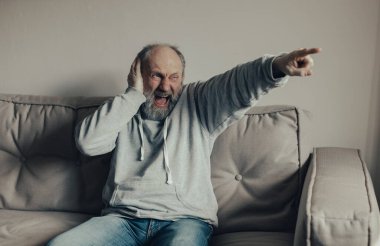 Ukraynalı korkmuş, gri saçlı, orta yaşlı adam kulaklarını patlamalardan koruyor..