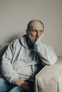 Ukraynalı gri saçlı adam savaşı düşünüyordu. Orta yaşlı bir adam kanepeye oturur ve düşünceli bir şekilde yan tarafa bakar..