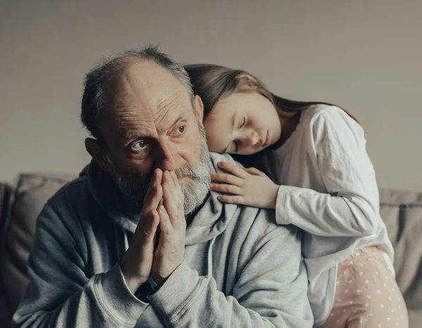 Ukraynalı endişeli orta yaşlı, ağlak adam korkmuş küçük torunu savunuyor. Torunu dedesine bakıyor. Savaşı durdurun. Ukrayna için dua et. Ukrayna 'yı destekliyoruz..