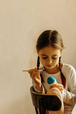 Ukraynalı bir kızın portresi. Çocuk yumurtayı mavi ve sarıya boyar. Çocuk ülkesini seviyor ve destekliyor. Paskalya yumurtalarını mavi ve sarı renklerle boyayan şirin bir kız çocuğu. Paskalya yumurtası taşıyan bir kızın elleri. Yakın plan..