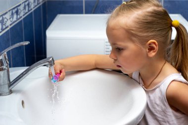 Küçük kız ellerini sabun ve suyla yıkıyor.