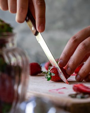 Mutfakta tatlı olarak çilek dilimleyen bir kadın.