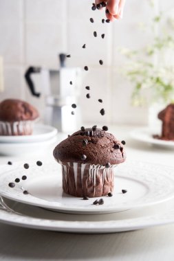 Ev yapımı kekin üzerine çikolata parçacıkları atan tanınmamış bir kadının eli. İtalyan bir kahve makinesiyle mutfak geçmişi.