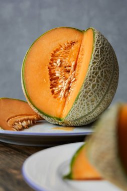 Japon kavunları, ballı kavun ya da beyaz tabakta kavun ve ahşap masa dilimleri. Gri arka plan. Yazın en iyi meyve. Meyve. Sağlıklı gıda konsepti. Ön- görünüm