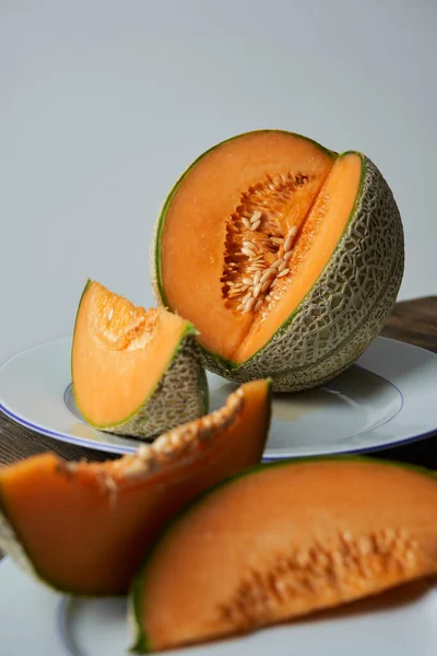 Japon kavunları, ballı kavun ya da beyaz tabakta kavun ve ahşap masa dilimleri. Beyaz arka plan. Yazın en iyi meyve. Meyve. Sağlıklı gıda konsepti. Ön- görünüm