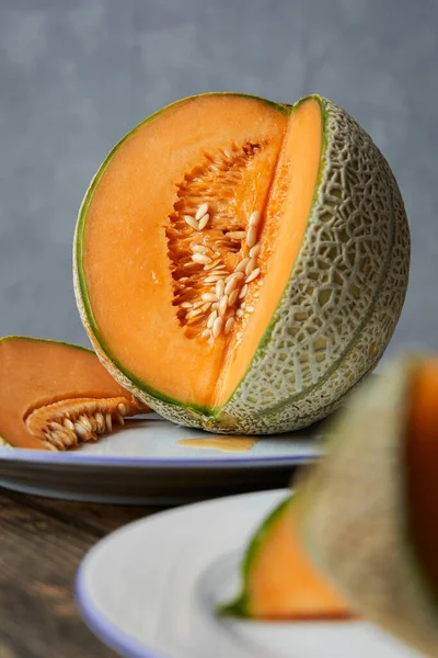 Japon kavunları, ballı kavun ya da beyaz tabakta kavun ve ahşap masa dilimleri. Gri arka plan. Yazın en iyi meyve. Meyve. Sağlıklı gıda konsepti. Ön- görünüm