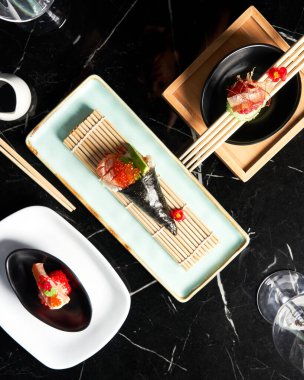 Düz manzaralı restoranda bir kavanoz soya sosuyla servis edilen suşi parçaları. Yiyecek, Japon mutfağı konsepti.
