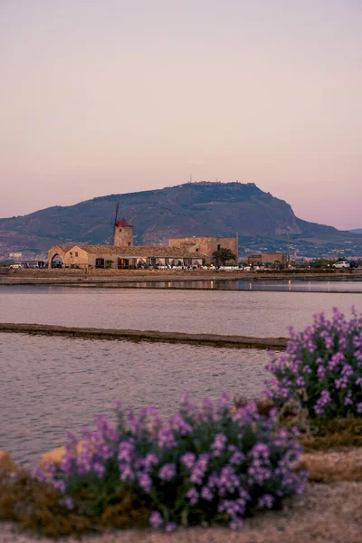 Trapani, Sicilya, İtalya 'da arka planda Erice Dağı ile geleneksel tuz tavalarının manzarası, su kaldırma değirmeni gibi tarihi mimari, eski baraj ve deniz suyuyla dolu göletler. Sicilya Adası 'nda tuz işe yarıyor..