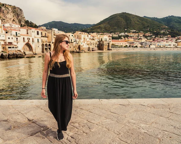 Güneşli bir bahar gününde İtalya 'nın Palermo ilindeki Sicilya adasının ortaçağ köyünde gülümseyen güneş gözlüklü güzel sarışın kadın..