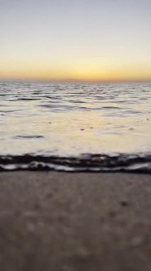 Deniz suyunun üzerinde gün batımını izleyeceğiz. Alacakaranlıkta gökyüzünde altın güneş ve deniz dalgaları kıyıya doğru koşuyor.