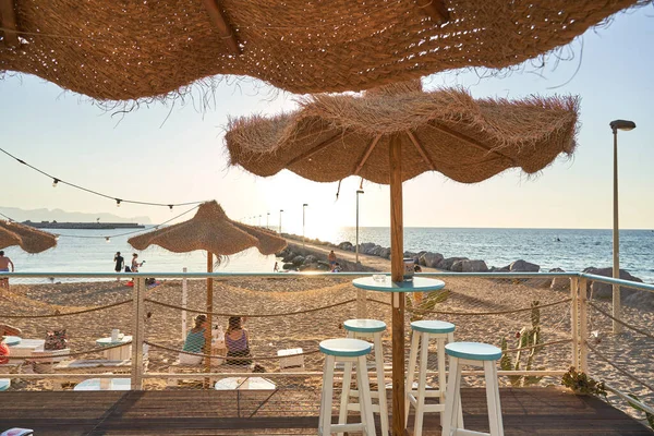 View on empty bar table against sunset at the beach. Summer time in Italy