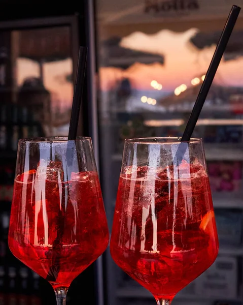 Two glasses of orange fresh spritz drink cocktail on a beach bar with sea and the reflection of the sea blurred background. Food and drink concept