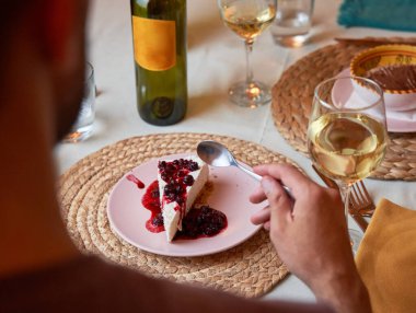 Unrecognizable man eating delicious homemade cheesecake served as dessert in an elegant Italian restaurant. Food and lifestyle concept