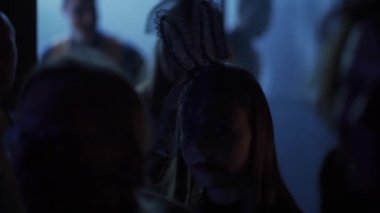 Sochi, Rusya - 01 Kasım 2020: Farklı kostümlü insanlar bir Cadılar Bayramı partisinde karanlık bir odaya girerler. Kadın gizemli bir şekilde gülümsüyor..