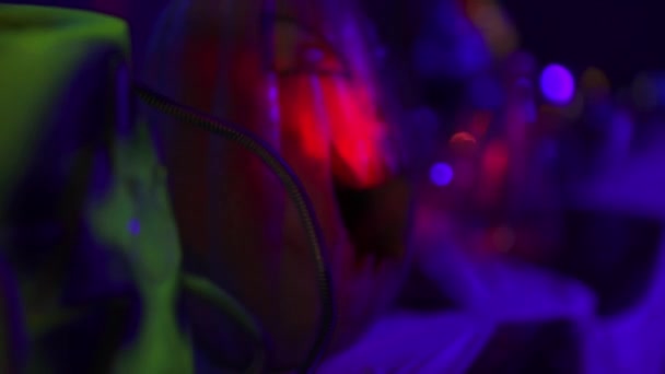 一个有着邪恶雕刻的笑容的大南瓜站在黑暗的房间背景的桌子上 有着五彩斑斓的灯光 万圣节派对的概念 — 图库视频影像