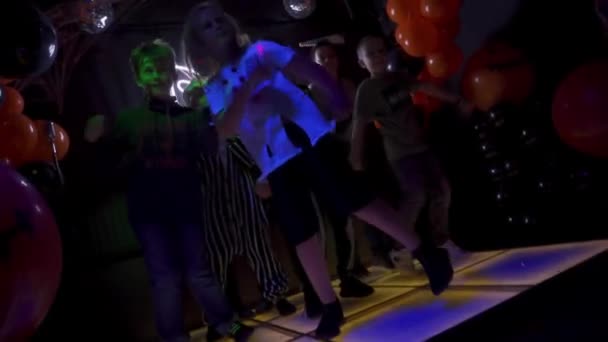 俄罗斯索契 2020年11月1日 一群快乐的年轻人在夜晚儿童俱乐部的灿烂的舞台上跳舞 万圣节派对上 脸上有化妆品的男孩们在黑暗的房间里穿梭于气球之间 — 图库视频影像