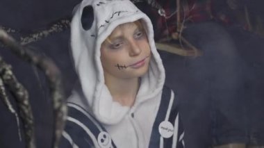 Sochi, Rusya - Kasım 01 2020: Korku makyajlı genç çocuk siyah ve beyaz iskelet takım elbise giyerek karanlık arka planda yakın plan görüntüsü oluşturdu. Cadılar Bayramı partisi. Tatil konsepti. Gece kulübü içeride.