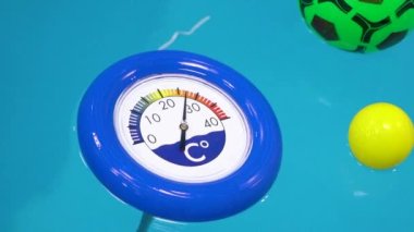Mavi termometre ve havuzda yüzen yüzme topları. Görüntüyü kapat.