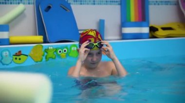 Young Caucasian kid goes down the stairs to the pool, wear swim glasses. Concept of active and healthy life.