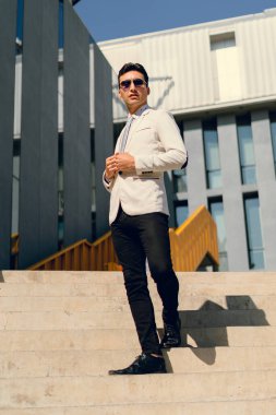 İki renkli kot pantolonlu, siyah beyaz kravatlı ve gözlüklü bir adam..