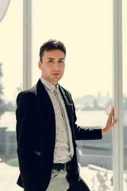 İki renkli kot pantolonlu, siyah beyaz kravatlı ve gözlüklü bir adam..