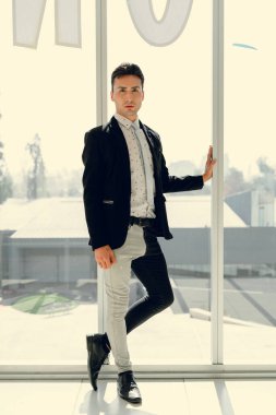 İki renkli kot pantolonlu, siyah beyaz kravatlı ve gözlüklü bir adam..