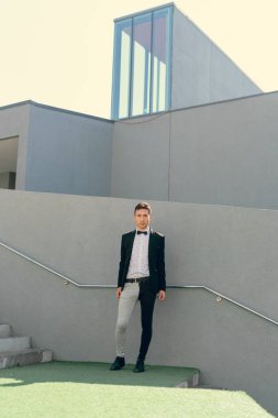 İki renkli kot pantolonlu, siyah beyaz kravatlı ve gözlüklü bir adam..