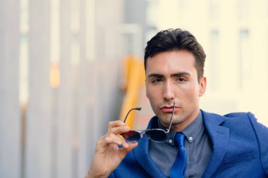 İki renkli kot pantolonlu, siyah beyaz kravatlı ve gözlüklü bir adam..