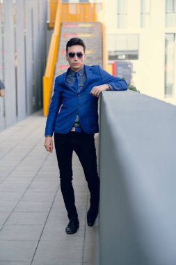 İki renkli kot pantolonlu, siyah beyaz kravatlı ve gözlüklü bir adam..