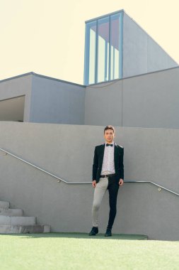 İki renkli kot pantolonlu, siyah beyaz kravatlı ve gözlüklü bir adam..