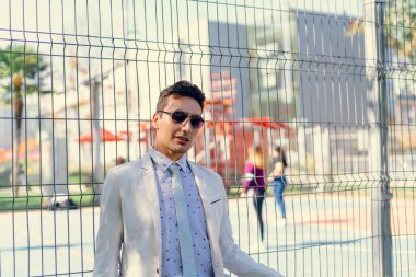 İki renkli kot pantolonlu, siyah beyaz kravatlı ve gözlüklü bir adam..