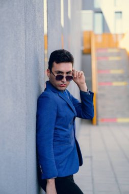 İki renkli kot pantolonlu, siyah beyaz kravatlı ve gözlüklü bir adam..