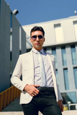 İki renkli kot pantolonlu, siyah beyaz kravatlı ve gözlüklü bir adam..