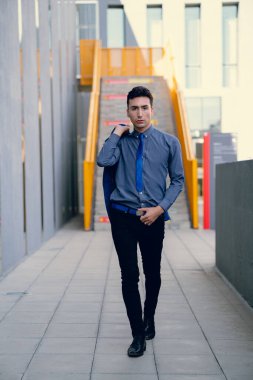 İki renkli kot pantolonlu, siyah beyaz kravatlı ve gözlüklü bir adam..