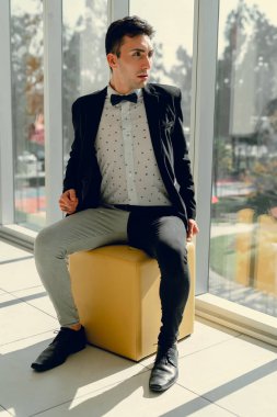 İki renkli kot pantolonlu, siyah beyaz kravatlı ve gözlüklü bir adam..