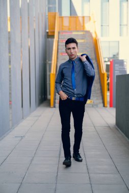 İki renkli kot pantolonlu, siyah beyaz kravatlı ve gözlüklü bir adam..