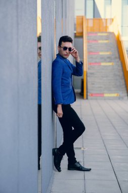 İki renkli kot pantolonlu, siyah beyaz kravatlı ve gözlüklü bir adam..