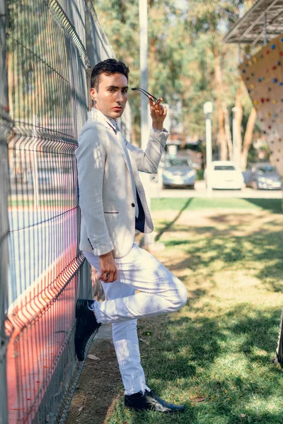 İki renkli kot pantolonlu, siyah beyaz kravatlı ve gözlüklü bir adam..