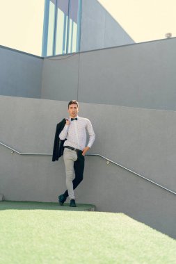 İki renkli kot pantolonlu, siyah beyaz kravatlı ve gözlüklü bir adam..