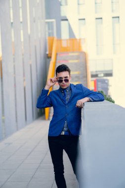 İki renkli kot pantolonlu, siyah beyaz kravatlı ve gözlüklü bir adam..