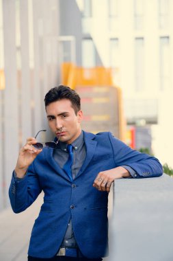 İki renkli kot pantolonlu, siyah beyaz kravatlı ve gözlüklü bir adam..