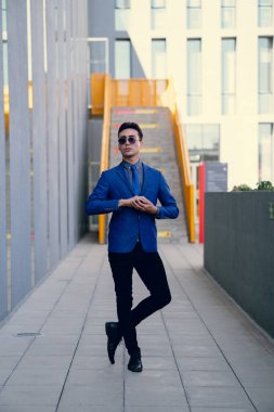 İki renkli kot pantolonlu, siyah beyaz kravatlı ve gözlüklü bir adam..