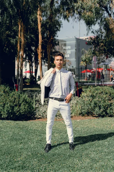 İki renkli kot pantolonlu, siyah beyaz kravatlı ve gözlüklü bir adam..