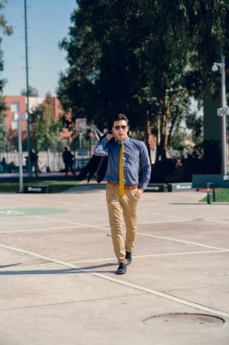 İki renkli kot pantolonlu, siyah beyaz kravatlı ve gözlüklü bir adam..