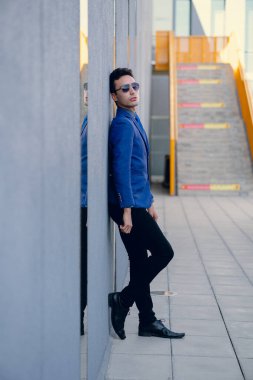 İki renkli kot pantolonlu, siyah beyaz kravatlı ve gözlüklü bir adam..